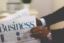 person wearing suit reading business newspaper